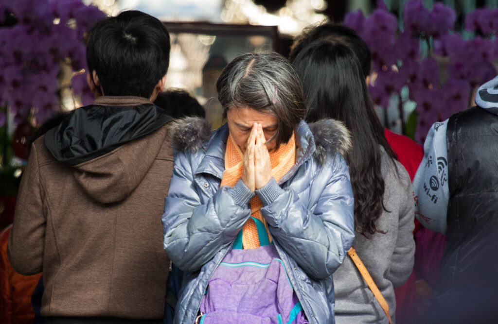 A woman praying at a temple in Asia.